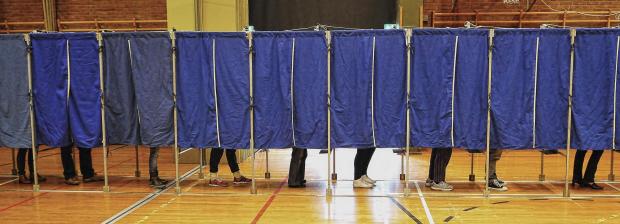 Billede af valgbokse med personer der stemmer i